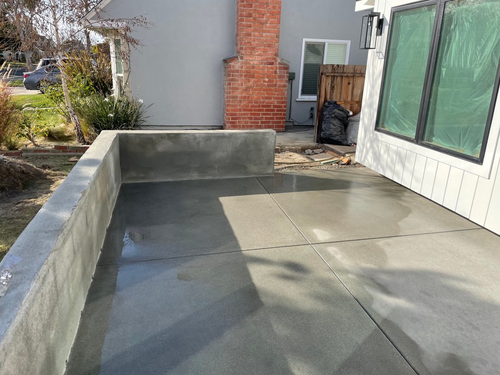 New concrete patio and block planter wall beside a home